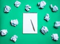 white notebook with pen on a green background among paper balls. The concept of generating ideas, inventing new ideas. Paper balls Royalty Free Stock Photo