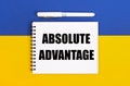 A white notebook with the text ABSOLUTE ADVANTAGE and a white pen on a blue and yellow background Royalty Free Stock Photo