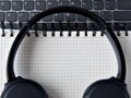 White notepad with keyboard and headphones background