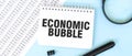 White notepad and magnifier on the financial documentation. Text ECONOMIC BUBBLE. Business concept Royalty Free Stock Photo