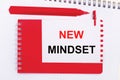 On a white notepad, a red pen, a red notepad and a white sheet of paper with the text NEW MINDSET Royalty Free Stock Photo