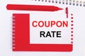 On a white notepad, a red pen, a red notepad and a white sheet of paper with the text COUPON RATE Royalty Free Stock Photo