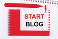 On a white notepad, a red pen, a red notepad and a white sheet of paper with the text START BLOG Royalty Free Stock Photo