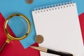 White notepad with a stylish pen, magnifying glass on a red background. Copy space Royalty Free Stock Photo