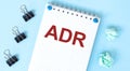 White notepad with text ADR and office tools on the blue background Royalty Free Stock Photo