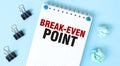White notepad with text BREAK-EVEN POINT and office tools on the blue background Royalty Free Stock Photo