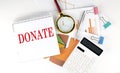 White notepad text DONATE with diagram,chart,calculator on the white background Royalty Free Stock Photo