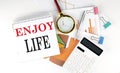 White notepad text ENJOY LIFE with diagram,chart,calculator on the white background