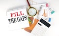 White notepad text FILL THE GAPS with diagram,chart,calculator on the white background Royalty Free Stock Photo