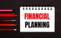 A white notepad with the text FINANCIAL PLANNING, written on a white notepad next to red pens, pencils and markers on a black Royalty Free Stock Photo