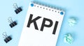 White notepad with text KPI and office tools on the blue background Royalty Free Stock Photo