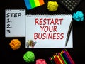 White notes with inscription `restart your business` and `step 1, 2, 3` on beautiful black table, colored paper, colored penci