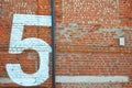 Painted white figure, number five on a red brick wall Royalty Free Stock Photo