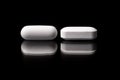White oblong pharmaceutical pills on black background