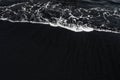 White ocean foam on black sand volcanic texture