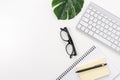 White office desk table with blank notebook, computer keyboard and other office supplies. Top view with copy space Royalty Free Stock Photo