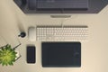 White office desk table with computer keyboard, mouse, monitor, graphic tablet, smartphone, succulent plant and other office