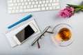 White office desk table with keyboard, phone, writing supplies and flowers