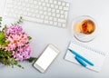 White office desk table with keyboard, phone, writing supplies and flowers