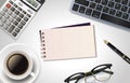 White office desk table with laptop, calculator,pen, cup of coffee,notepad and glass. Top view with copy space, flat lay. Royalty Free Stock Photo