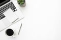 White office desk table with notebook over a laptop computer with coffee and supplies. Top view with copy space, flat lay Royalty Free Stock Photo