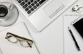 White office desk table top view, laptop, cup of coffee, cellphone, glasses, pencil notepad and white background. Royalty Free Stock Photo