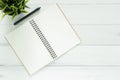 White office desk wooden table background with notebooks and pens and plant.