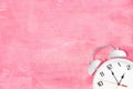 White old fashioned alarm clock with twin bells and ringer on pink texture as background