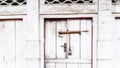 White old house door closed with diminished paint and rusty doorknob and lock