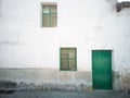 An white old house facade with green door and two little windows Royalty Free Stock Photo