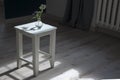 White old stool is in the middle of the room with a vase with flowers of burdock. Horizontal frame Royalty Free Stock Photo