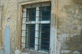 White old wooden window behind a brown rusty grate on the concrete wall Royalty Free Stock Photo