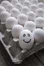 White and one smile eggs in a cardboard box.