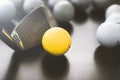 white and one yellow golf balls on black floor. individuality an