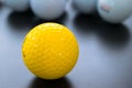 white and one yellow golf balls on black floor. individuality an