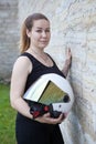 White open face helmet with mirror shield in hands of beautiful woman motorcyclist, portrait near stone wall