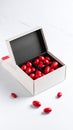 White open gift box filled with shiny red candies and scattered sweets on a white marble surface. Royalty Free Stock Photo