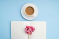 White open notebook for notes, white cup of coffee with milk, pink flower on a blue background, place for text, copy space. Top vi Royalty Free Stock Photo