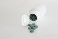 White open pill bottle on table and some pills spreaded. Empty copy space Royalty Free Stock Photo