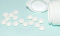 White open plastic jar with a bunch of white scattered pills on a light blue background, medicine concept, banner Royalty Free Stock Photo