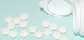 White open plastic jar with a bunch of white scattered pills on a light blue background, medicine concept, banner Royalty Free Stock Photo