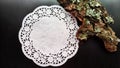White openwork carved paper napkin on a black background and bark with moss. Abstract background and texture for the Royalty Free Stock Photo