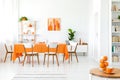 White and orange dining room with painting on the wall, bookshelf in the corner and green plant Royalty Free Stock Photo