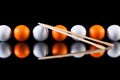 White and orange golf balls with bamboo chopsticks Royalty Free Stock Photo