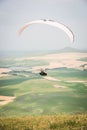 White orange paraglide with a paraglider in a cocoon against the background of fields of the sky and clouds. Paragliding