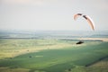 White orange paraglide with a paraglider in a cocoon against the background of fields of the sky and clouds. Paragliding Royalty Free Stock Photo