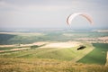 White orange paraglide with a paraglider in a cocoon against the background of fields of the sky and clouds. Paragliding Royalty Free Stock Photo