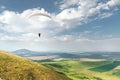 White orange paraglide with a paraglider in a cocoon against the background of fields of the sky and clouds. Paragliding