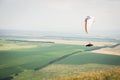 White orange paraglide with a paraglider in a cocoon against the background of fields of the sky and clouds. Paragliding