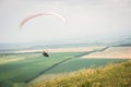 White orange paraglide with a paraglider in a cocoon against the background of fields of the sky and clouds. Paragliding